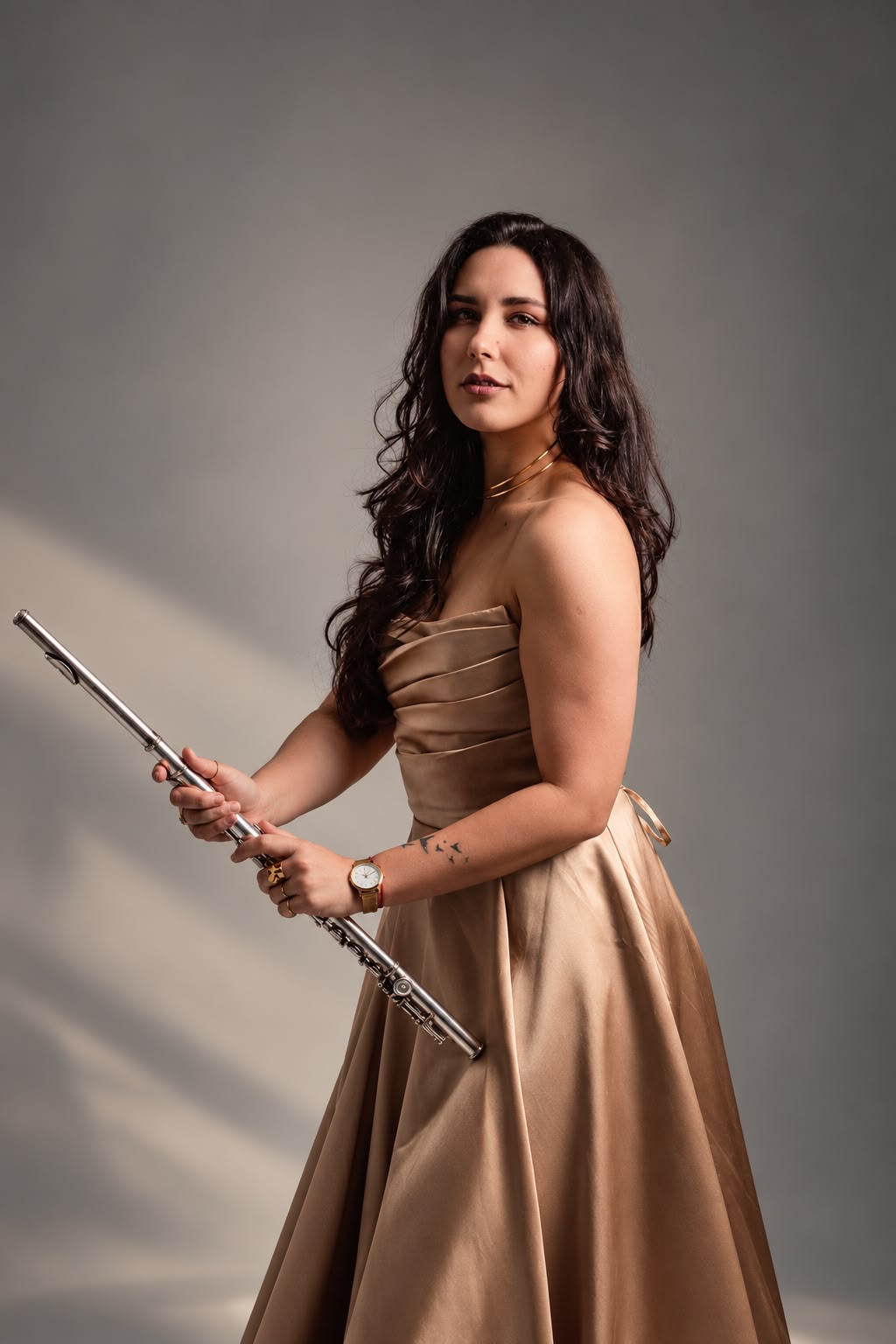 Legna Otero holding her flute, wearing a gold gown